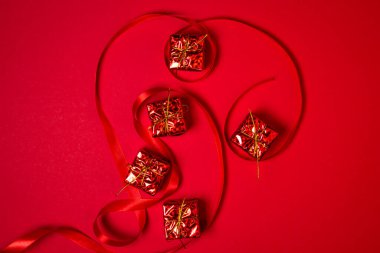 Kırmızı hediyeler ve kırmızı arka planda kırmızı kurdele. Tatil süslemeleri. Noel konsepti. 