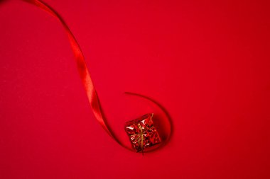 Kırmızı arka planda kırmızı kurdeleli kırmızı hediye. Tatil süslemeleri. Noel konsepti. 