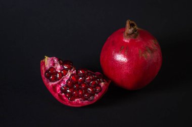 Siyah arka planda nar. Kesik Nar, bütünün yanında. Kırmızı meyve