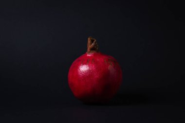 Siyah arka planda nar. Çerçevenin ortasına bir nar. Kırmızı meyve