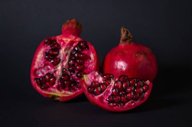 Siyah arka planda nar. Kesik Nar, bütünün yanında. Kırmızı meyve