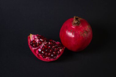 Siyah arka planda nar. Kesik Nar, bütünün yanında. Kırmızı meyve