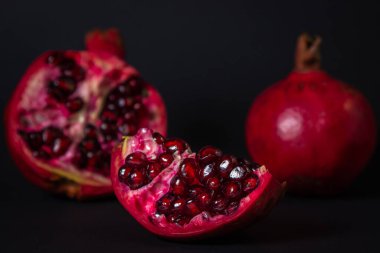 Siyah arka planda nar. Kesik Nar, bütünün yanında. Kırmızı meyve