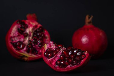 Siyah arka planda nar. Kesik Nar, bütünün yanında. Kırmızı meyve