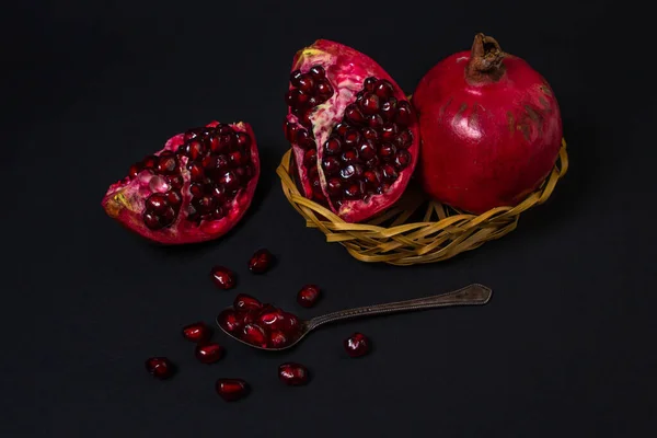 Pomegranate on a black background. Cut Pomegranate. Red fruit. Pomegranate full spoon