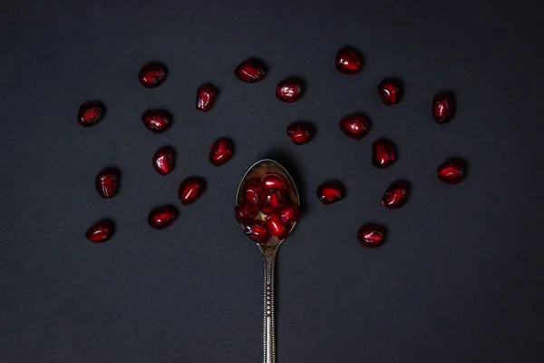 黒の背景にザクロ ザクロでいっぱいのスプーン 赤い果実 — ストック写真