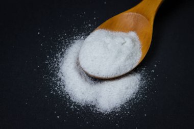 Tahta kaşık ve tuz. Yakınlarda biraz tuz dökülmüş. Aşırı tuz alımı. Kaba tuz.
