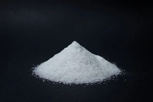 Siyah arka planda bir yığın tuz. Aşırı tuz alımı. Kaba tuz.