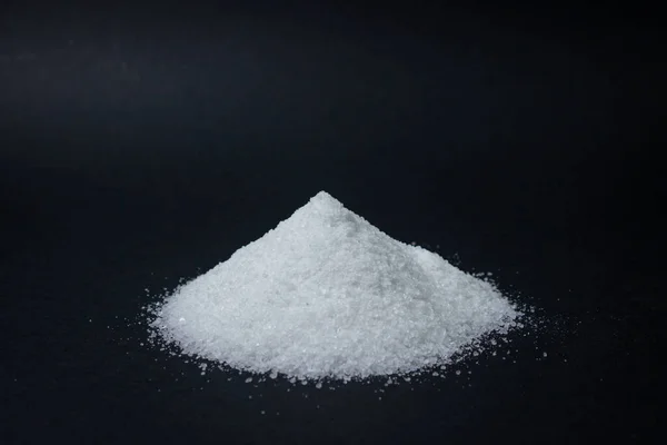 Siyah arka planda bir yığın tuz. Aşırı tuz alımı. Kaba tuz.