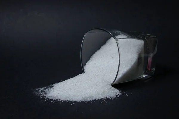 黒を背景に塩 塩がガラスから注がれた 過剰な塩分摂取 — ストック写真