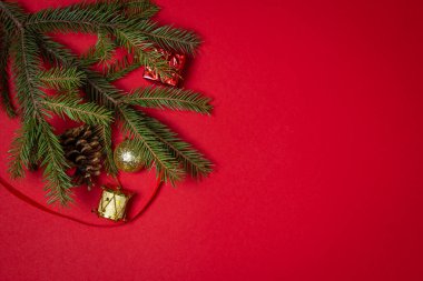 Kırmızı arka planda Noel süslemeleri olan Noel ağacı dalları. Noel arkaplanı. Yeni yıl konsepti. Yazıt ya da logo için bir yer var.