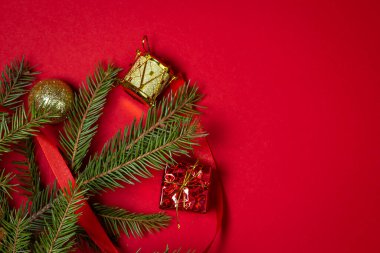 Kırmızı arka planda Noel süslemeleri olan Noel ağacı dalları. Noel arkaplanı. Yeni yıl konsepti. Yazıt ya da logo için bir yer var.