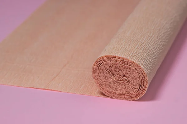 Colored corrugated paper. Roll of beige corrugated paper on a pink background. paper product