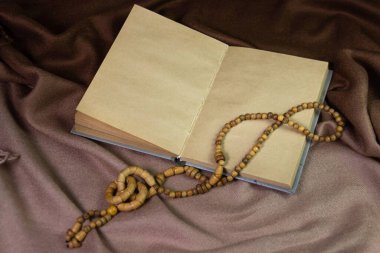 Kahverengi kumaşın üzerindeki boş defter. Eski kağıt defter. Defterde tahta bir süsleme var.