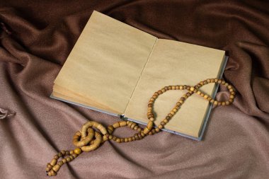 Kahverengi kumaşın üzerindeki boş defter. Eski kağıt defter. Defterde tahta bir süsleme var.