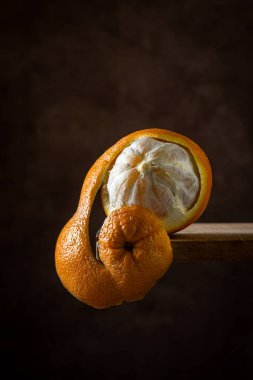 Ahşap bir yüzeyde turuncu. Citrus meyvesi. Turuncu yarı soyulmuş. Portakal kabuğu sarkıyor