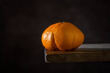 Ahşap bir yüzeyde soyulmuş mandalina. Citrus meyvesi. Mandalina kabuğu soyulmuş mandalinanın üzerinde yatıyor.