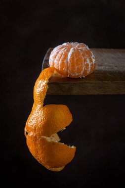 Ahşap bir yüzeyde soyulmuş mandalina. Citrus meyvesi. Mandalina kabuğu yanında asılı.