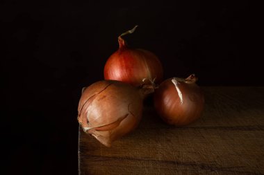 Tahta bir yüzeyde soğanlar. Sağlıklı sebzeler. Üç Soğan yan yana yatar.