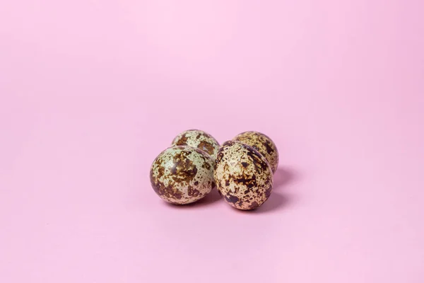 Quail eggs on a pink background. Healthy food. Several quail eggs lie next to each other