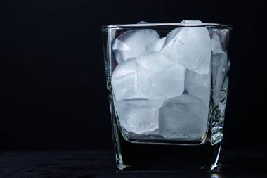 Siyah arka planda buzlu bir bardak. Buz kırıntıları. Viski bardağı.