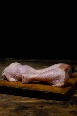 Tahtada çiğ tavuk bacağı. Siyah arka planda tavuk bacağı. Tavuk eti.