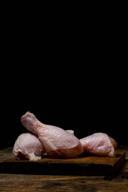 Tahtada çiğ tavuk bacağı. Siyah arka planda tavuk bacağı. Tavuk eti.