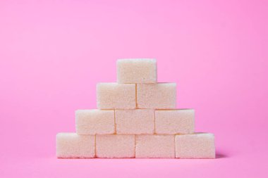 Pembe arka planda küp şekerler. Şeker piramidi. Rafine şeker.