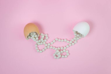 Kırık yumurtadan yayılmış beyaz boncuklar. Pembe arka planda boncuklar. Kadınların bijouterie 'si. Günlük dekorasyon.
