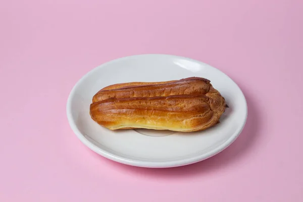 Eclairs Sobre Fondo Rosa Una Eclair Plato Blanco Desayuno Dulce —  Fotos de Stock