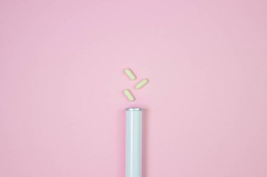 Beyaz haplar pembe arka planda bir mataranın yanında. Sağlık konsepti. Sağlık hizmetleri.