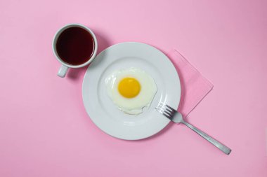 Pembe arka planda çırpılmış yumurta. Beyaz tabakta sahanda yumurta. Bir fincan kahveyle nefis bir kahvaltı.