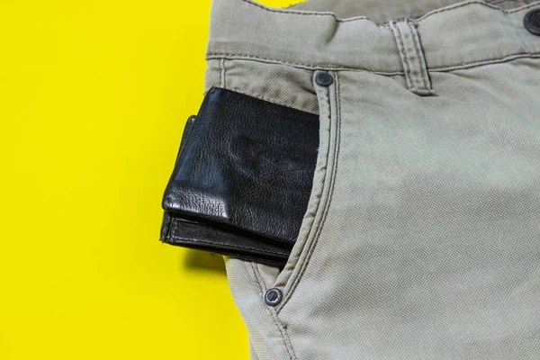 財布は私のズボンのポケットから突き出している 男性用アクセサリー 黒の財布 黄色の背景の服 — ストック写真
