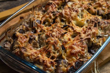 Siyah arka planda pişmiş tavuk. Mantarlı ve peynirli fırında tavuk. Bardakta yiyecek.