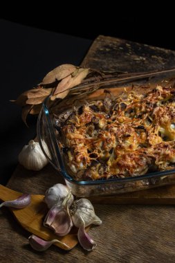 Siyah arka planda pişmiş tavuk. Mantarlı ve peynirli fırında tavuk. Bardakta yiyecek.