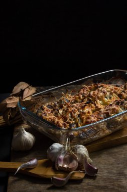 Siyah arka planda pişmiş tavuk. Mantarlı ve peynirli fırında tavuk. Bardakta yiyecek.