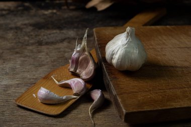 Siyah arka planda sarımsak. Sarımsağın yanında sarımsak ezmesi. Tahta bir spatulada sarımsak.