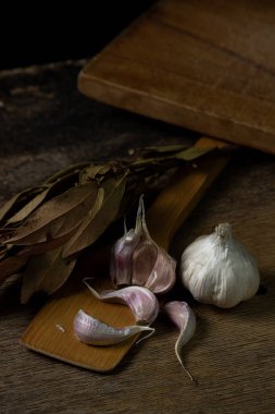 Siyah arka planda sarımsak. Sarımsağın yanında sarımsak ezmesi. Tahta bir spatulada sarımsak.