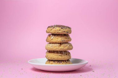 Pembe arka planda kurabiyeler. Beyaz tabakta serpiştirilmiş karamelli kurabiyeler. Susam tohumları serpin. Hafif tatlı.