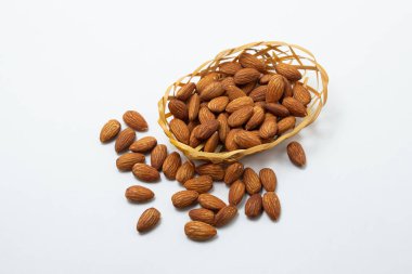 Beyaz arka planda badem. İzole bademler. Küçük bir sepette kavrulmuş badem.