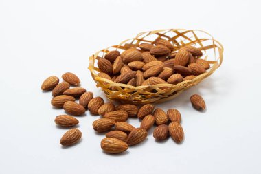Beyaz arka planda badem. İzole bademler. Küçük bir sepette kavrulmuş badem.