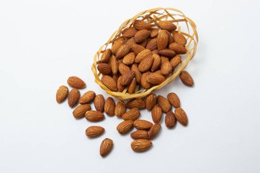 Beyaz arka planda badem. İzole bademler. Küçük bir sepette kavrulmuş badem.