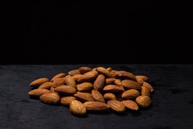 Siyah arka planda badem. İzole bademler. Kavrulmuş badem yığını