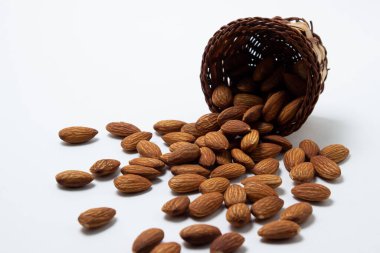 Beyaz arka planda badem. İzole bademler. Kavrulmuş badem sepetinden döküldü.