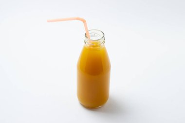 Beyaz arka planda meyve suyu olan cam şişe. Doğal mango suyu. Tazeleyici içecek.