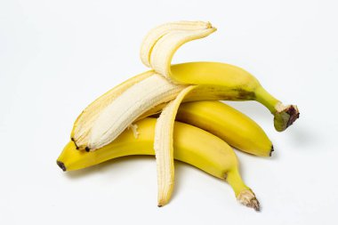 Beyaz arka planda muzlar. Taze sarı muzlar. Soyulmuş bir muz bütün muzun üzerinde yatar. Egzotik meyve
