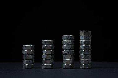 Siyah arka planda fındık cıvataları. sivri uçlu. Fındık cıvataları birkaç sütuna istiflenmiş.