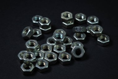 Siyah arka planda fındık cıvataları. sivri uçlu. Fındık cıvataları siyah yüzeye saçılmış..