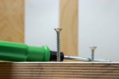 Ahşap. Tahta levhalar ve çalışma aletleri. Metal vida ve tornavida. Kendi kendine dokunan vida tahtadan bir torbaya vidalanmış..