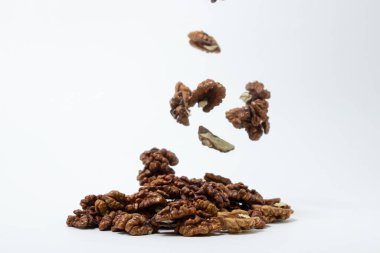 Beyaz arka planda soyulmuş ceviz. Kabuğu soyulmuş bir ceviz, ceviz yığınının üstüne düşer. Besleyici yemekler.